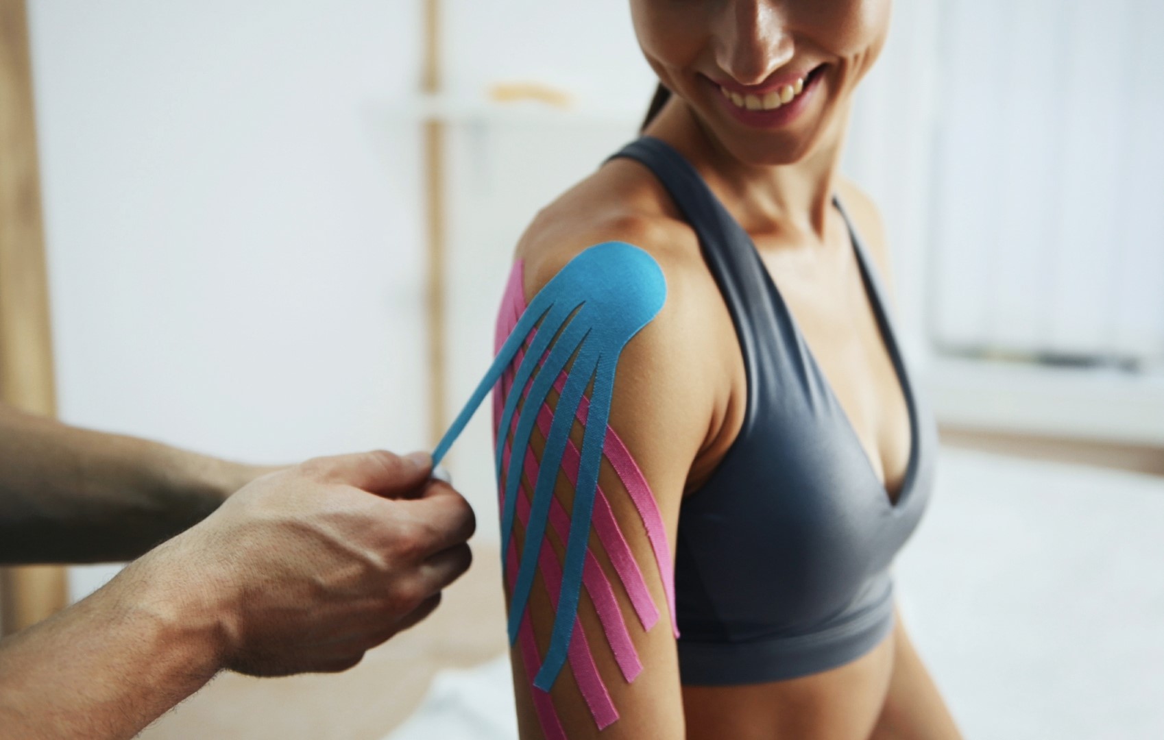 doctor-helps-woman-by-shoulder-treatment-with-kine-42N9YZV